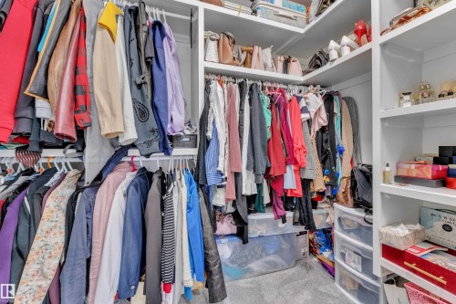 Custom closet system featuring multiple hanging rods, integrated shelving, and carpet flooring - 8025 174A Avenue, Edmonton, AB - Indoor With Storage