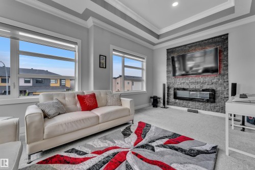 Living space featuring a tray ceiling, recessed lighting, and expansive windows - 8025 174A Avenue, Edmonton, AB - Indoor Photo Showing Living Room With Fireplace