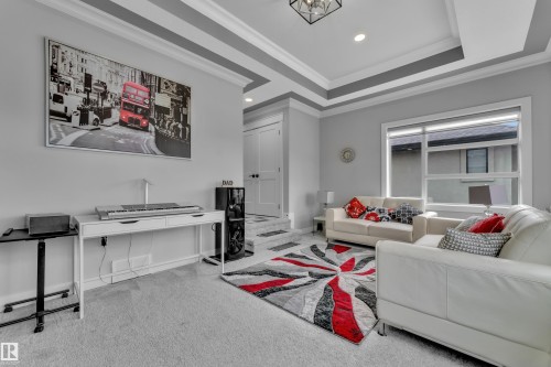 Expansive living area featuring a tray ceiling with crown molding, recessed lighting, and a large window - 8025 174A Avenue, Edmonton, AB - Indoor