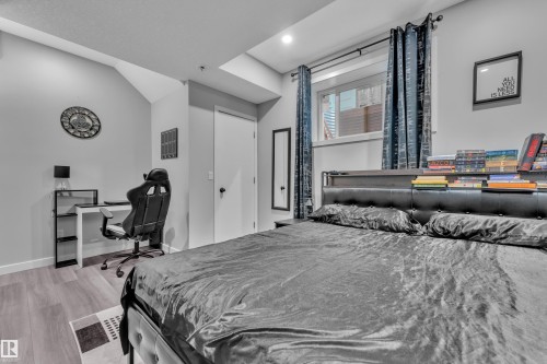 Spacious room featuring wood-finish flooring, a contemporary window with drapes, a built-in shelf above the bed, and recessed lighting - 8025 174A Avenue, Edmonton, AB - Indoor Photo Showing Bedroom