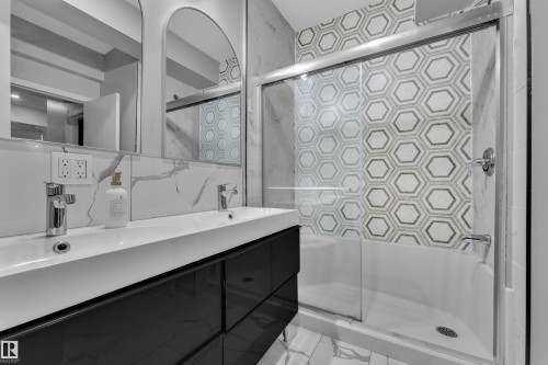 Contemporary bathroom featuring a white rectangular dual-sink vanity with a dark finish base, accented by dual arched mirrors and a white marbling-patterned backsplash - 8025 174A Avenue, Edmonton, AB - Indoor Photo Showing Bathroom