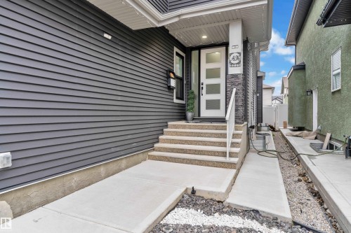 Contemporary exterior featuring dark gray siding and a white entry door with frosted glass panels - 8025 174A Avenue, Edmonton, AB - Outdoor