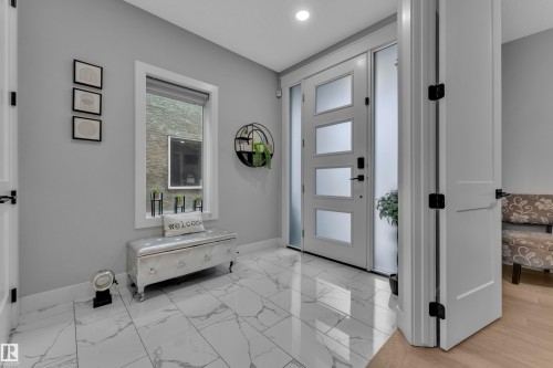 Entryway featuring large format marble-look tile flooring, a contemporary front door with frosted glass panels, and a sidelight - 8025 174A Avenue, Edmonton, AB - Indoor Photo Showing Other Room