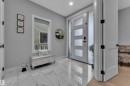 Entryway featuring large format marble-look tile flooring, a contemporary front door with frosted glass panels, and a sidelight - 8025 174A Avenue, Edmonton, AB  - Indoor Photo Showing Other Room 