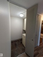 Compact utility space featuring tiled flooring, a built-in base cabinet with a countertop, an upper cabinet, and louvered bifold doors - 