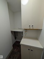 Utility area with a built-in counter, upper and lower cabinetry, and dark-toned tile flooring - 