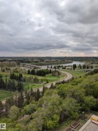 Expansive natural landscape featuring a winding river, mature trees, and distant cityscape - 