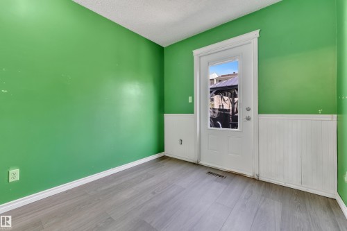 Interior space featuring wood-finish flooring, white beadboard wainscoting, and a white exterior door with a window pane - 4536 35A Avenue, Edmonton, AB - Indoor Photo Showing Other Room