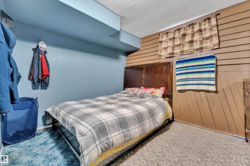 Two-tone wall treatment featuring blue painted vertical paneling and horizontal wood-finish paneling - 4536 35A Avenue, Edmonton, AB - Indoor Photo Showing Bedroom