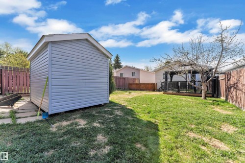 Spacious backyard featuring a storage shed with siding, a wooden deck with black railings, and perimeter fencing - 4536 35A Avenue, Edmonton, AB - Outdoor