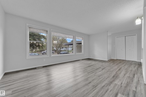 Spacious room featuring wood-finish flooring, light grey wall paint, and white baseboards - 2119 85 Street, Edmonton, AB - Indoor Photo Showing Living Room