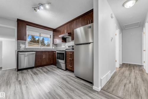 Kitchen featuring wood-finish cabinetry, stainless steel appliances, and a subway tile backsplash - 2119 85 Street, Edmonton, AB - Indoor Photo Showing Kitchen