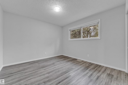 Light gray walls with wood-finish flooring, a white window frame, and a ceiling-mounted light fixture - 2119 85 Street, Edmonton, AB - Indoor Photo Showing Other Room
