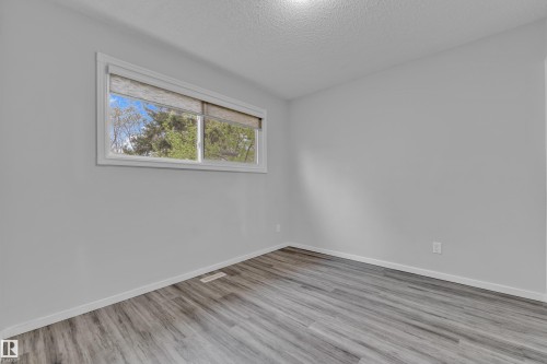 Neutral wall paint, wood-finish flooring, white baseboards, and a window with roller shades - 2119 85 Street, Edmonton, AB - Indoor Photo Showing Other Room