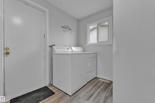 Dedicated laundry area featuring wood-finish flooring, a white window frame, and light gray walls - 2119 85 Street, Edmonton, AB - Indoor Photo Showing Laundry Room