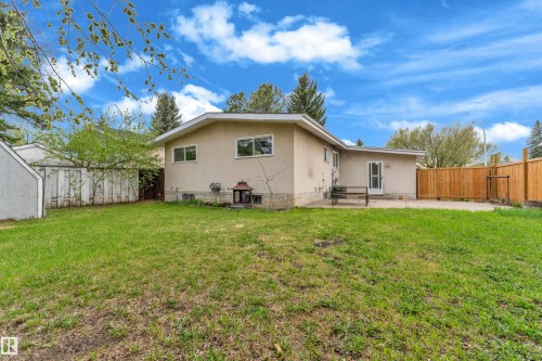 Expansive lawn area with a neutral-toned stucco exterior and a stone foundation accent - 2119 85 Street, Edmonton, AB - Outdoor