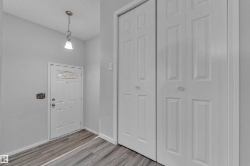 Entryway featuring wood-finish flooring, a white paneled entry door with a decorative transom, and a pendant light fixture - 2119 85 Street, Edmonton, AB - Indoor Photo Showing Other Room