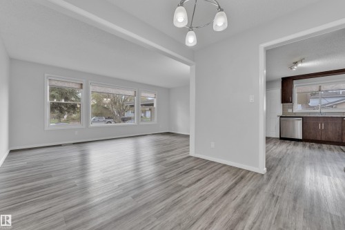 Bright living space featuring wood-finish flooring and a three-window bank - 2119 85 Street, Edmonton, AB - Indoor Photo Showing Living Room
