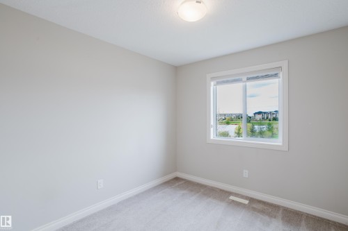Carpeted room featuring a white-framed window, neutral painted walls, white trim, and a surface-mounted ceiling light fixture - 328 West Haven Drive, Leduc, AB - Indoor Photo Showing Other Room