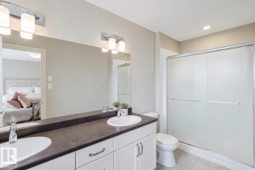 Double vanity with integrated sinks and dark countertop, complemented by dual mirror-mounted light fixtures - 328 West Haven Drive, Leduc, AB - Indoor Photo Showing Bathroom