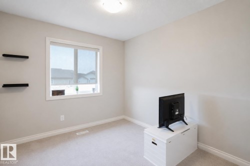 Room featuring neutral-toned walls, a single window with a roller shade, and two wall-mounted shelves - 328 West Haven Drive, Leduc, AB - Indoor Photo Showing Other Room