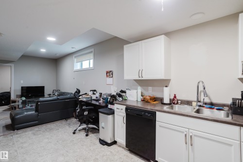 Kitchenette featuring white cabinetry, a double basin stainless steel sink, a black dishwasher, and laminate countertops - 328 West Haven Drive, Leduc, AB - Indoor