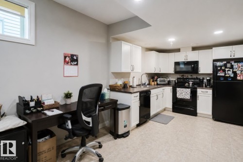 Kitchenette featuring white cabinetry, dark countertops, and black appliances - 328 West Haven Drive, Leduc, AB - Indoor