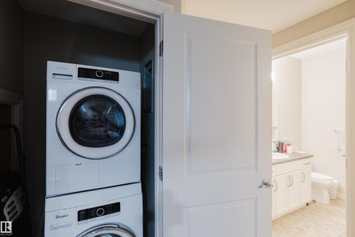 Compact laundry area featuring a stacked washer and dryer unit - 328 West Haven Drive, Leduc, AB - Indoor Photo Showing Laundry Room