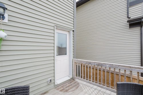 Outdoor deck featuring wood railing, light grey siding, and a white exterior door with glass insert - 328 West Haven Drive, Leduc, AB - Outdoor With Exterior