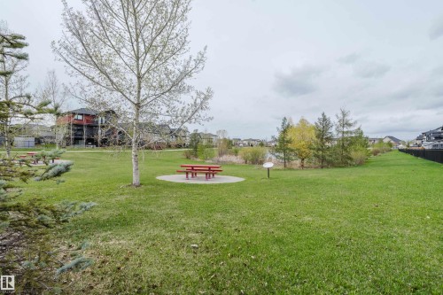 Expansive green space featuring a picnic area with a red table and bench set on a circular paved pad - 328 West Haven Drive, Leduc, AB - Outdoor With View