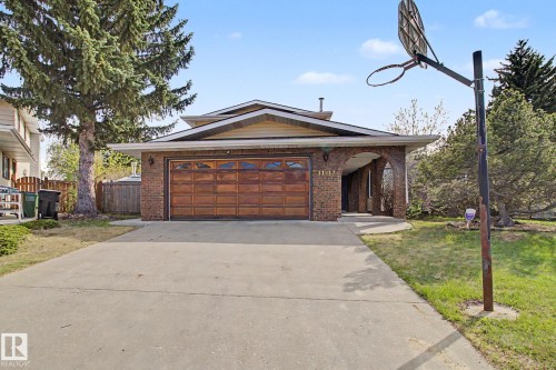 Brick exterior featuring a wood-panel garage door and an arched entryway - 11617 26 Avenue, Edmonton, AB - Outdoor