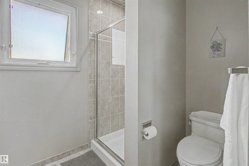 Shower enclosure with glass door, tile surround, and an integrated white shower pan - 11617 26 Avenue, Edmonton, AB - Indoor Photo Showing Bathroom