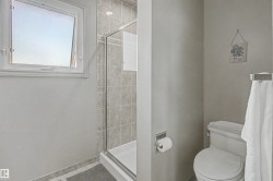 Shower enclosure with glass door, tile surround, and an integrated white shower pan - 