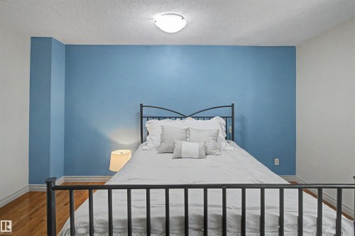 Hardwood-style flooring extends throughout this room with a textured ceiling - 11617 26 Avenue, Edmonton, AB - Indoor Photo Showing Bedroom