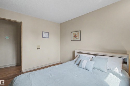 Bedroom featuring neutral wall paint, white baseboards, and wood-finish flooring extending into the hallway - 11617 26 Avenue, Edmonton, AB - Indoor Photo Showing Bedroom