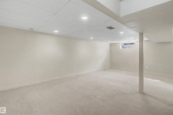 Spacious room featuring neutral carpeting, light-toned walls, and a drop ceiling with recessed lighting - 