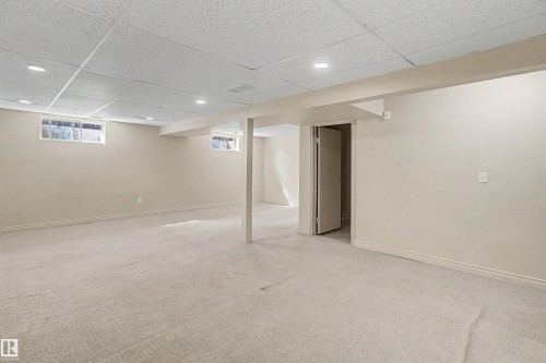 Spacious lower-level room featuring light-toned carpeting, neutral wall paint, and a drop ceiling with recessed lighting - 11617 26 Avenue, Edmonton, AB - Indoor Photo Showing Basement