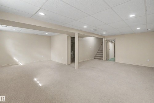 Spacious finished lower level featuring recessed lighting, light-colored carpeting, painted walls, a dropped ceiling, and a visible staircase - 11617 26 Avenue, Edmonton, AB - Indoor