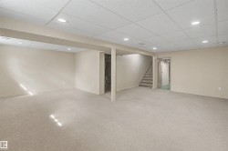 Spacious finished lower level featuring recessed lighting, light-colored carpeting, painted walls, a dropped ceiling, and a visible staircase - 