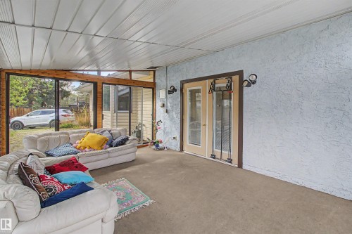 Enclosed patio space featuring large sliding glass doors, exposed wood beams, and textured wall finishes - 11617 26 Avenue, Edmonton, AB - Indoor Photo Showing Other Room