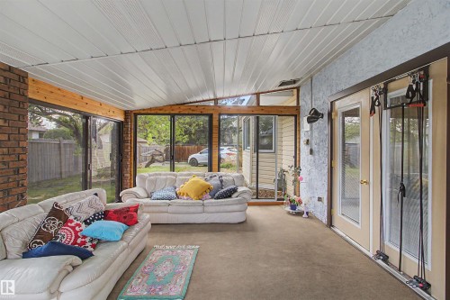 Sunroom featuring a pitched ceiling, full-height windows, a brick accent wall, and dual pane glass doors - 11617 26 Avenue, Edmonton, AB -  With Exterior