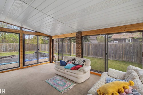 Sunroom with large sliding glass doors, exposed wood beams, brick accent pillars, and a neutral carpeted floor - 11617 26 Avenue, Edmonton, AB -  Photo Showing Other Room