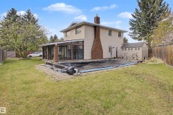Rear exterior featuring a sunroom addition, brick chimney, and a covered in-ground pool - 