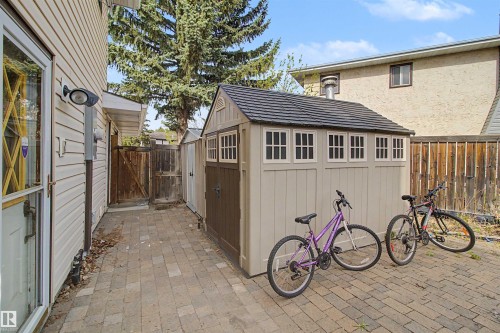 Paved stone walkway leading to a neutral-toned storage shed with decorative windows and dark brown double doors - 11617 26 Avenue, Edmonton, AB - Outdoor With Exterior