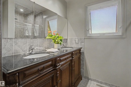 Double vanity with decorative wood-finish cabinetry and a dark countertop - 11617 26 Avenue, Edmonton, AB - Indoor Photo Showing Bathroom