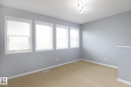 Neutral tone wall paint, light tan carpeting, and white baseboards - 9071 Scott Crescent, Edmonton, AB - Indoor Photo Showing Other Room