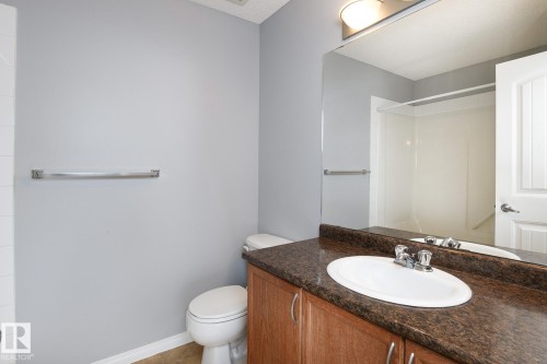 Full bathroom featuring a wood-finish vanity with a dark speckled countertop and oval undermount sink, a large wall-mounted mirror, and a white shower/tub combination - 9071 Scott Crescent, Edmonton, AB - Indoor Photo Showing Bathroom