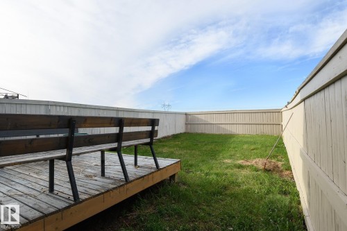 Expansive backyard featuring a wood deck, built-in wooden seating, a grass lawn, and full perimeter fencing - 9071 Scott Crescent, Edmonton, AB - Outdoor