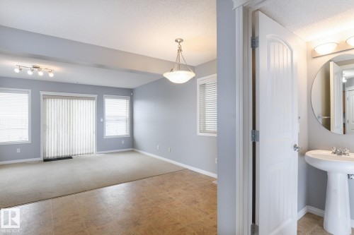Open living area featuring mixed flooring, track lighting, and a sliding glass door - 9071 Scott Crescent, Edmonton, AB - Indoor Photo Showing Other Room