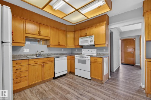 Kitchen featuring wood-finish cabinetry, light-toned countertops, and wood-finish flooring - 11901 42 Street, Edmonton, AB - Indoor Photo Showing Kitchen
